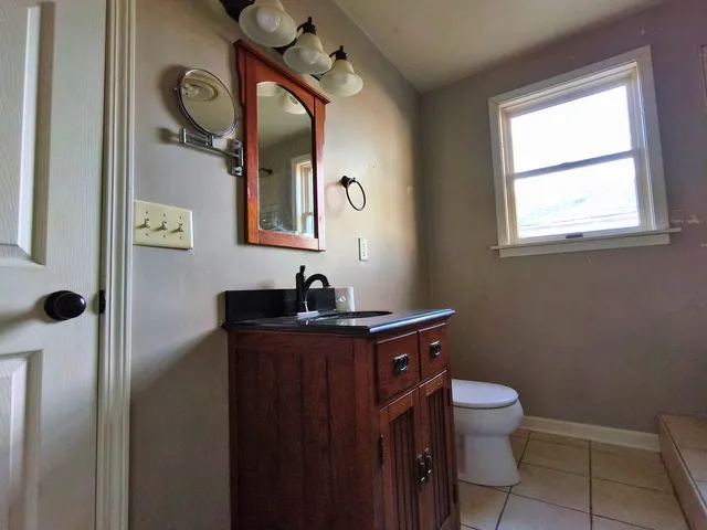 a bathroom with a toilet sink vanity and mirror