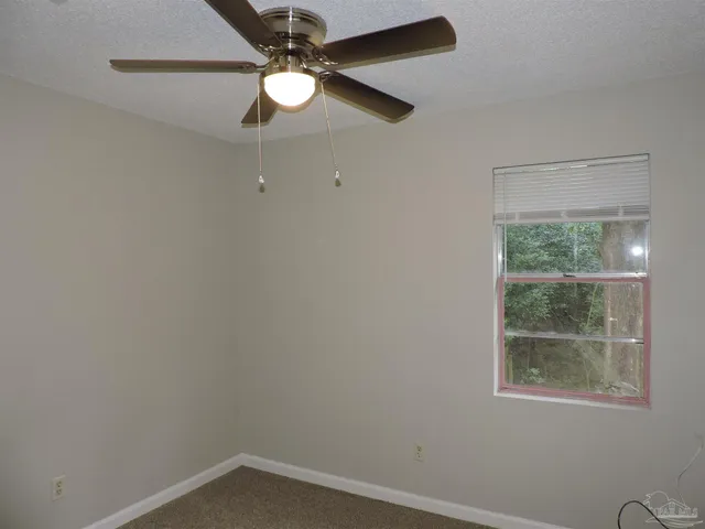 an empty room with a window and a fan