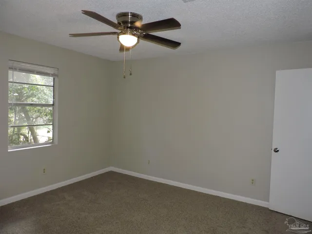 an empty room with a window and a fan