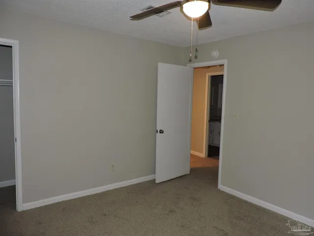 a view of an empty room with a chandelier fan