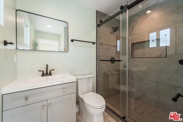 a bathroom with a toilet sink vanity and mirror
