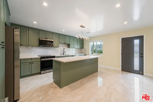 a large kitchen with stainless steel appliances kitchen island granite countertop a refrigerator and a stove top oven