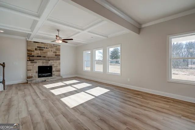 a view of an empty room with wooden floor fireplace and a window