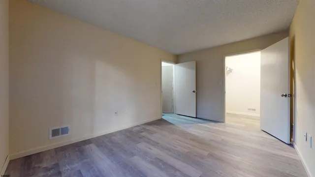 an empty room with wooden floor and windows