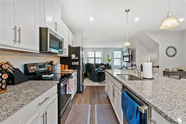 a kitchen with stainless steel appliances granite countertop a sink a stove and a wooden floors