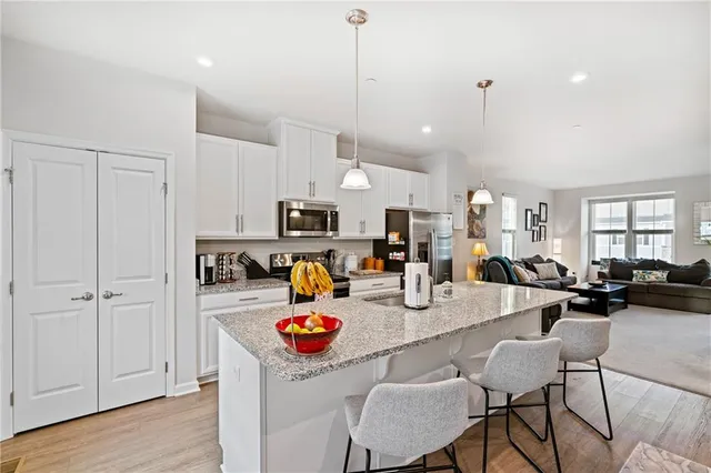 a kitchen with stainless steel appliances kitchen island granite countertop a stove and white cabinets with wooden floor