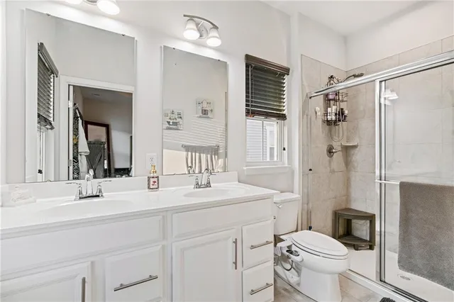 a bathroom with a sink a toilet a mirror and shower