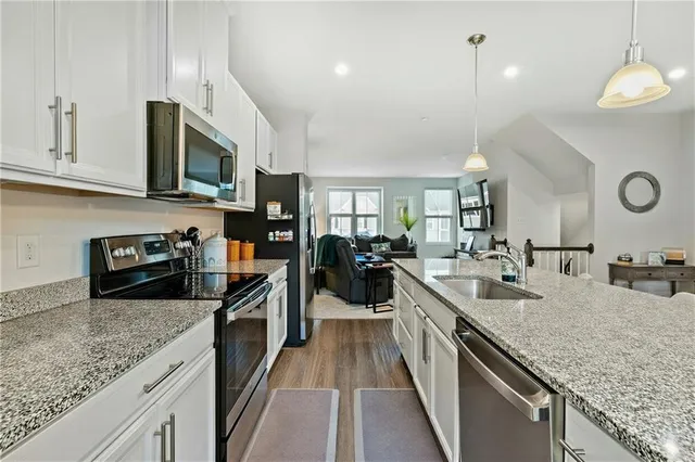 a large kitchen with stainless steel appliances granite countertop a lot of counter space and wooden floor