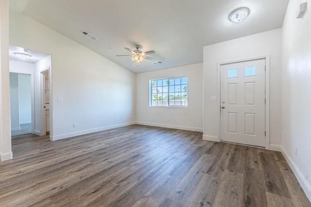 an empty room with wooden floor and windows