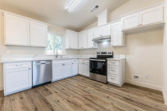 a kitchen with stainless steel appliances a white stove top oven sink and cabinets