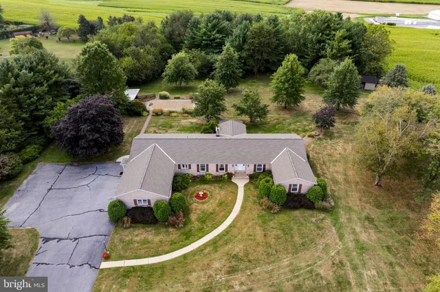 an aerial view of residential house with outdoor space and trees all around