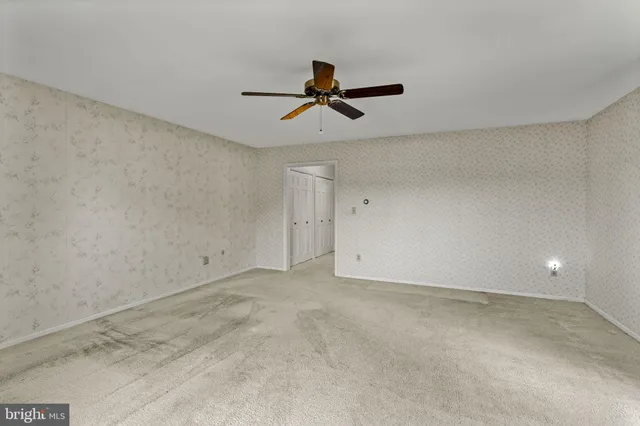 an empty room with a ceiling fan and window