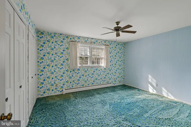 an empty room with windows and ceiling fan