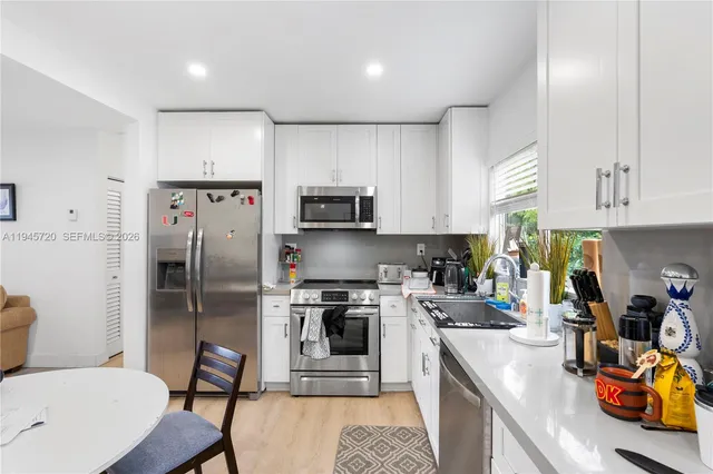 a room with stainless steel appliances a stove a sink cabinets and a window