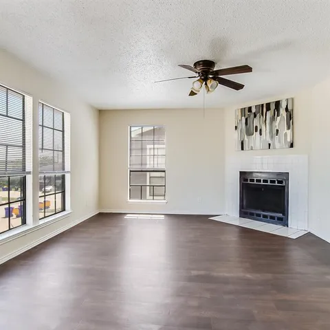 an empty room with windows a fireplace and wooden floor