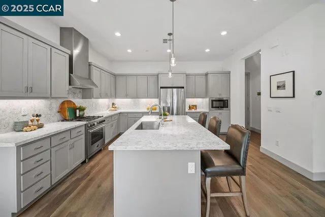 a kitchen with granite countertop a sink a center island stainless steel appliances and cabinets