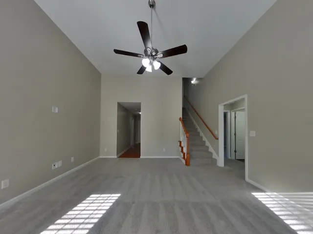 a view of an empty room with wooden floor and a ceiling fan