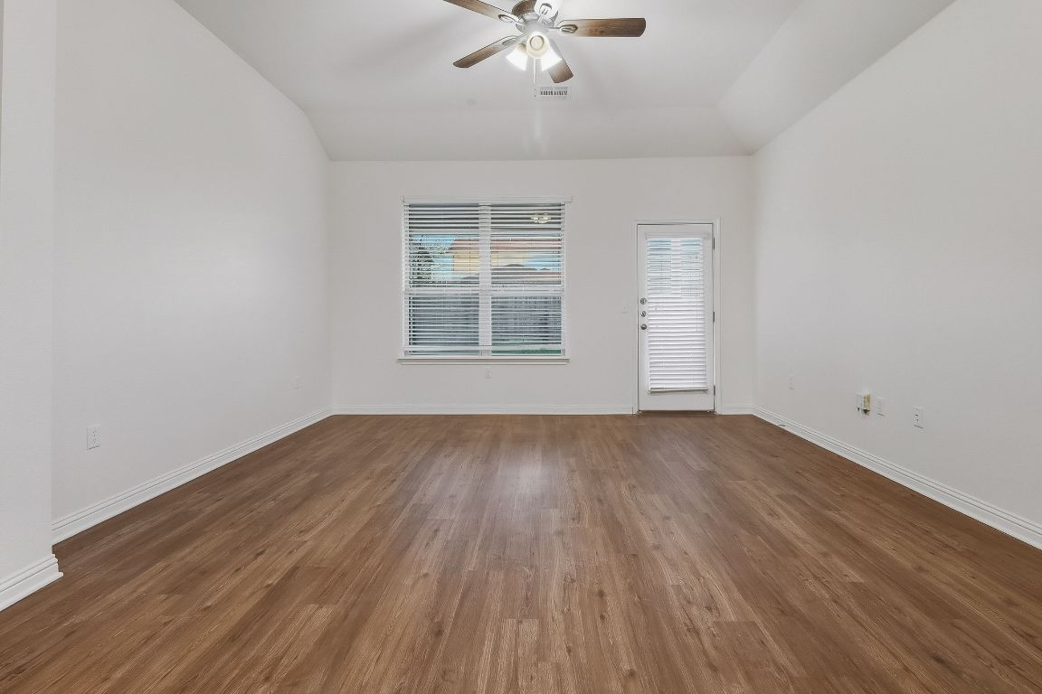 8001 Dampton Lane Austin, TX 78744 - Photo 8 of 38 an empty room with wooden floor chandelier fan and windows