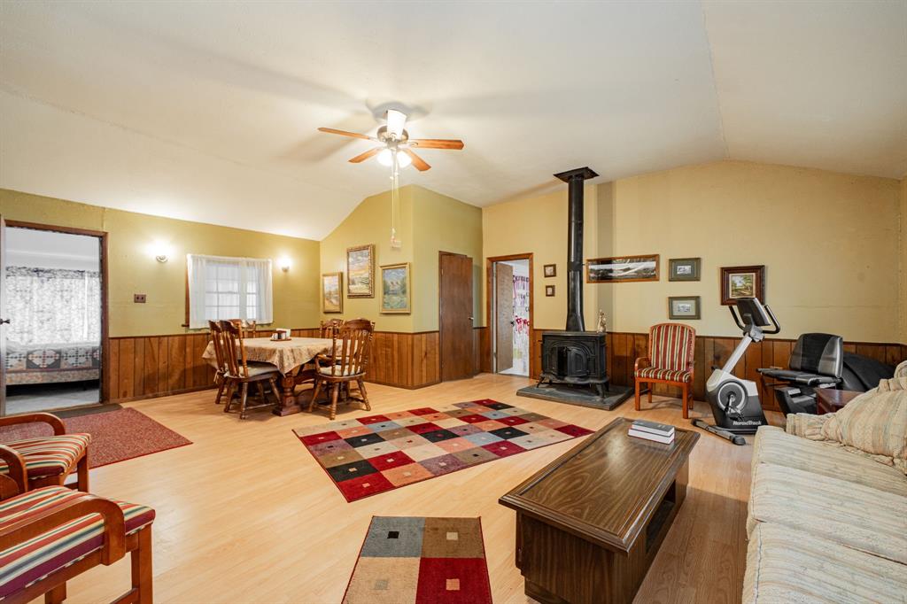 2712 Kleberg Road, Unit B Seagoville, TX 75159 - Photo 12 of 40 Living room with wainscoting, a ceiling fan, wood walls, wood finished floors, and a wood stove