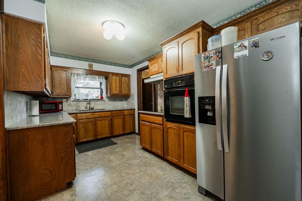 2712 Kleberg Road, Unit B Seagoville, TX 75159 - Photo 3 of 40 Kitchen featuring stainless steel refrigerator with ice dispenser, oven, light stone countertops, a textured ceiling, and wood finish cabinetry