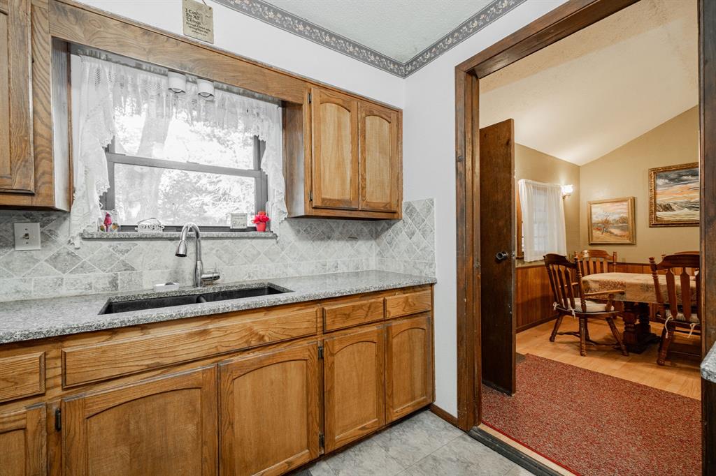 2712 Kleberg Road, Unit B Seagoville, TX 75159 - Photo 4 of 40 Kitchen featuring light stone counters, plenty of natural light, vaulted ceiling, wood finish cabinets, and decorative backsplash