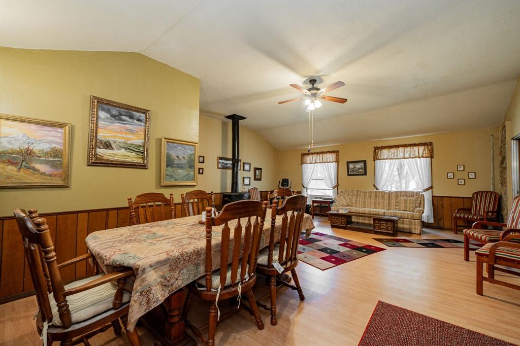 2712 Kleberg Road, Unit B Seagoville, TX 75159 - Photo 7 of 40 Dining area featuring a wood stove, lofted ceiling, a wainscoted wall, light wood-style floors, and ceiling fan