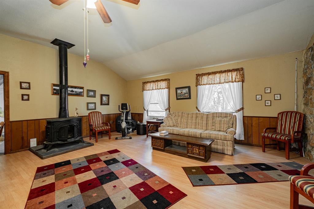 2712 Kleberg Road, Unit B Seagoville, TX 75159 - Photo 9 of 40 Living room with a wainscoted wall, wooden walls, a wood stove, light wood finished floors, and a ceiling fan
