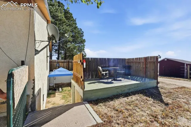 a view of a backyard with chairs potted plants and wooden fence