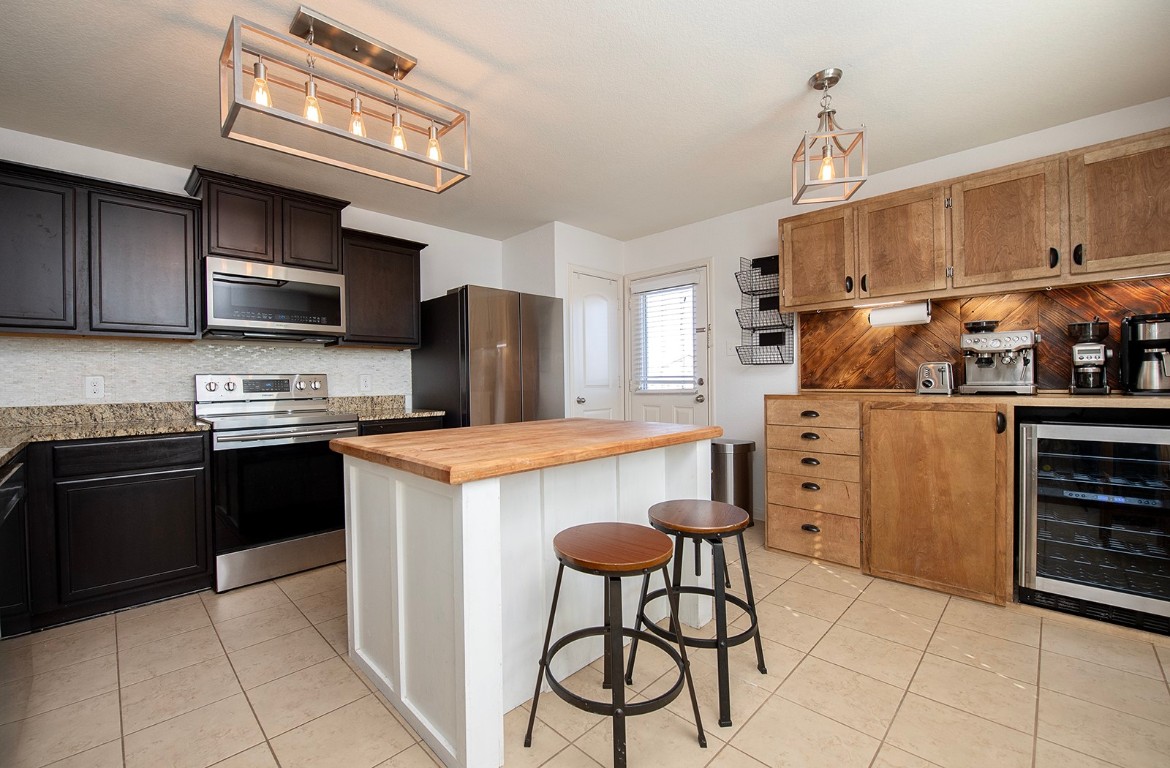 216 Millers Loop Jarrell, TX 76537 - Photo 11 of 31 Kitchen with appliances with stainless steel finishes, a breakfast bar area, wooden counters, wine cooler, and light tile patterned floors