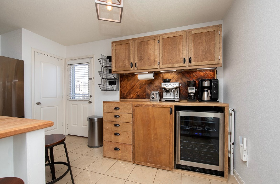 216 Millers Loop Jarrell, TX 76537 - Photo 13 of 31 Indoor dry bar with wine cooler, brown cabinets, tile flooring and wood counters