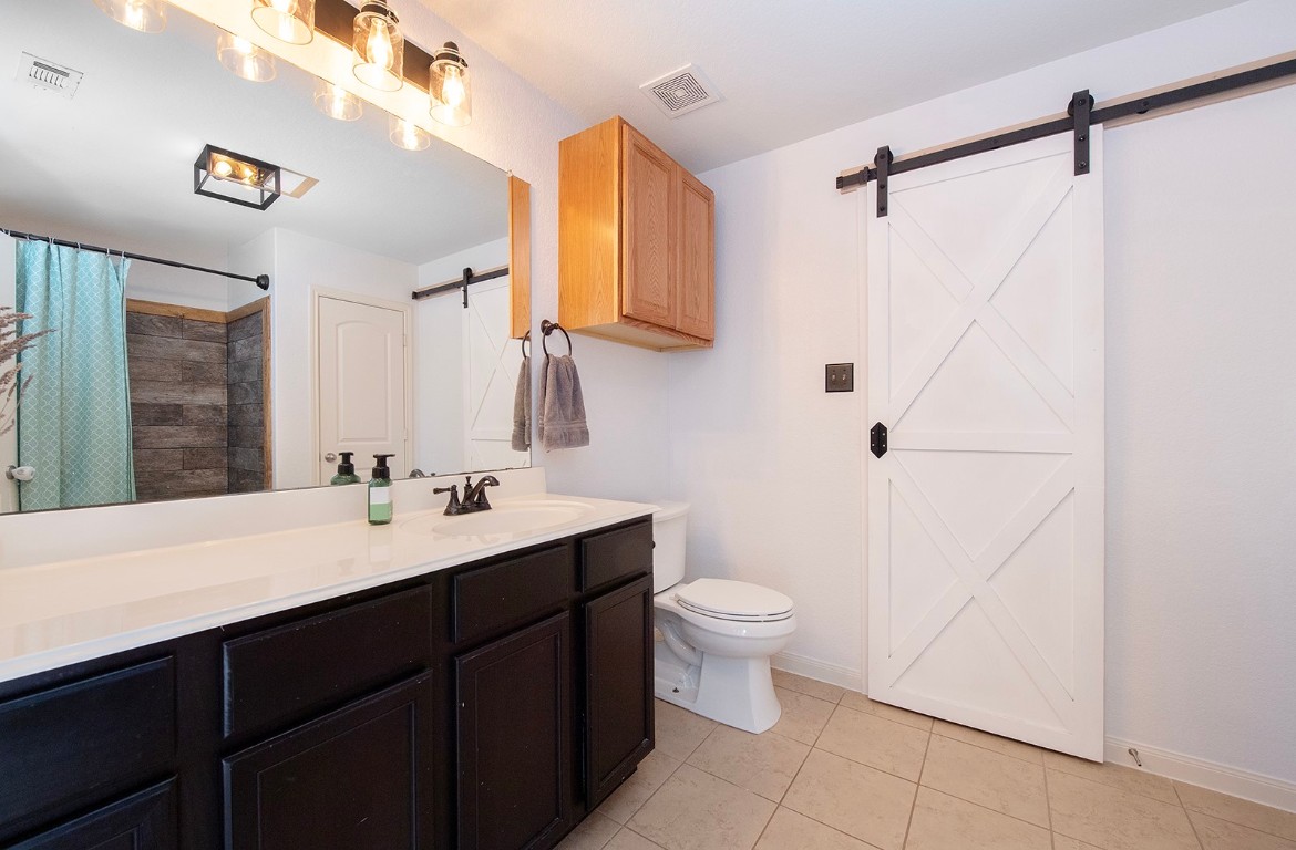 216 Millers Loop Jarrell, TX 76537 - Photo 15 of 31 Full bathroom featuring vanity, walk-in closet, wall cabinet, linen closet, tile flooring, and curtained shower