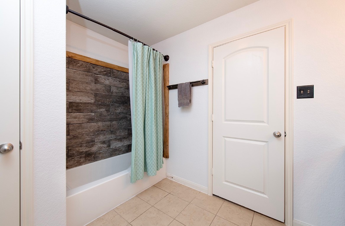 216 Millers Loop Jarrell, TX 76537 - Photo 16 of 31 Bathroom with shower / bathtub combination with curtain, walk-in closet, linen closet, wall cabinet and tile flooring