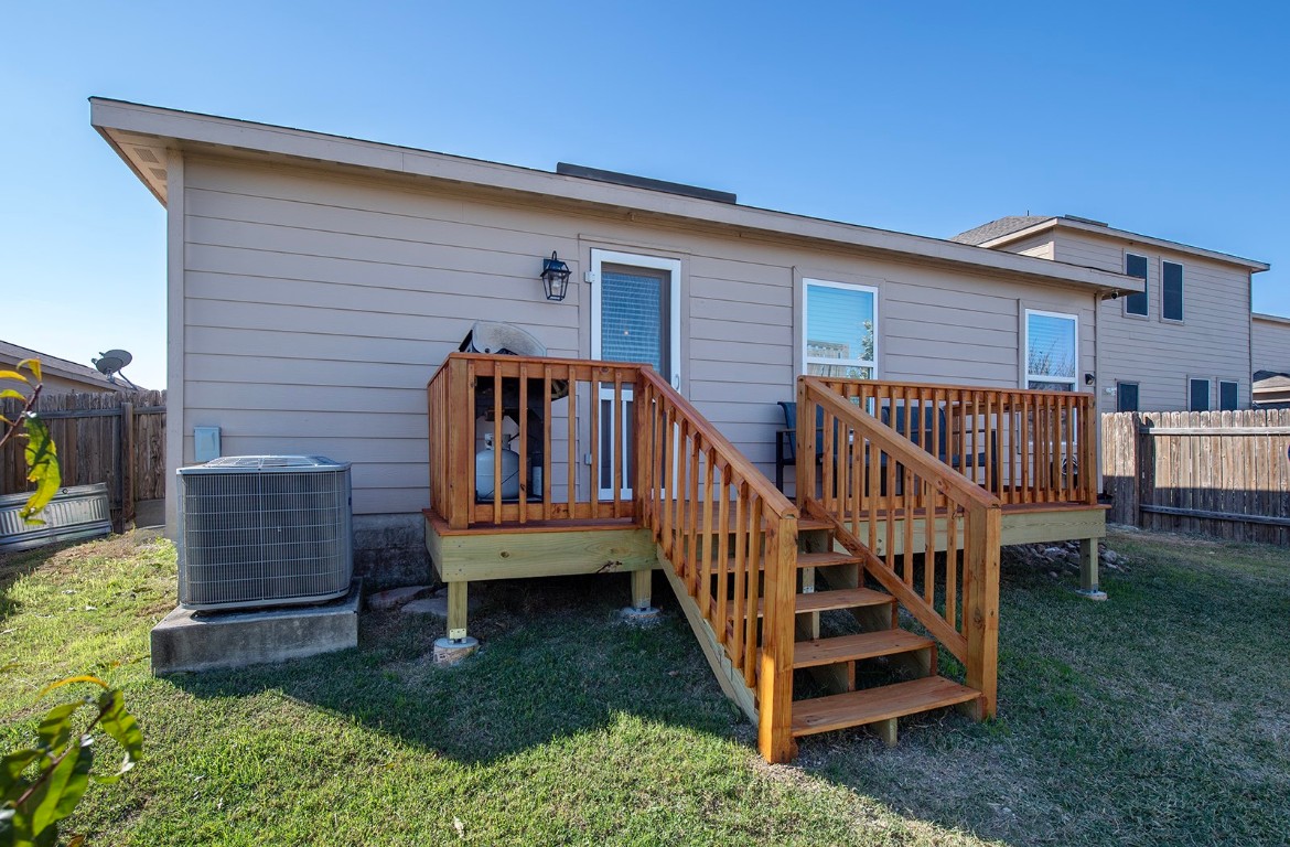 216 Millers Loop Jarrell, TX 76537 - Photo 26 of 31 Back of property featuring a fenced backyard, a deck, and stairway