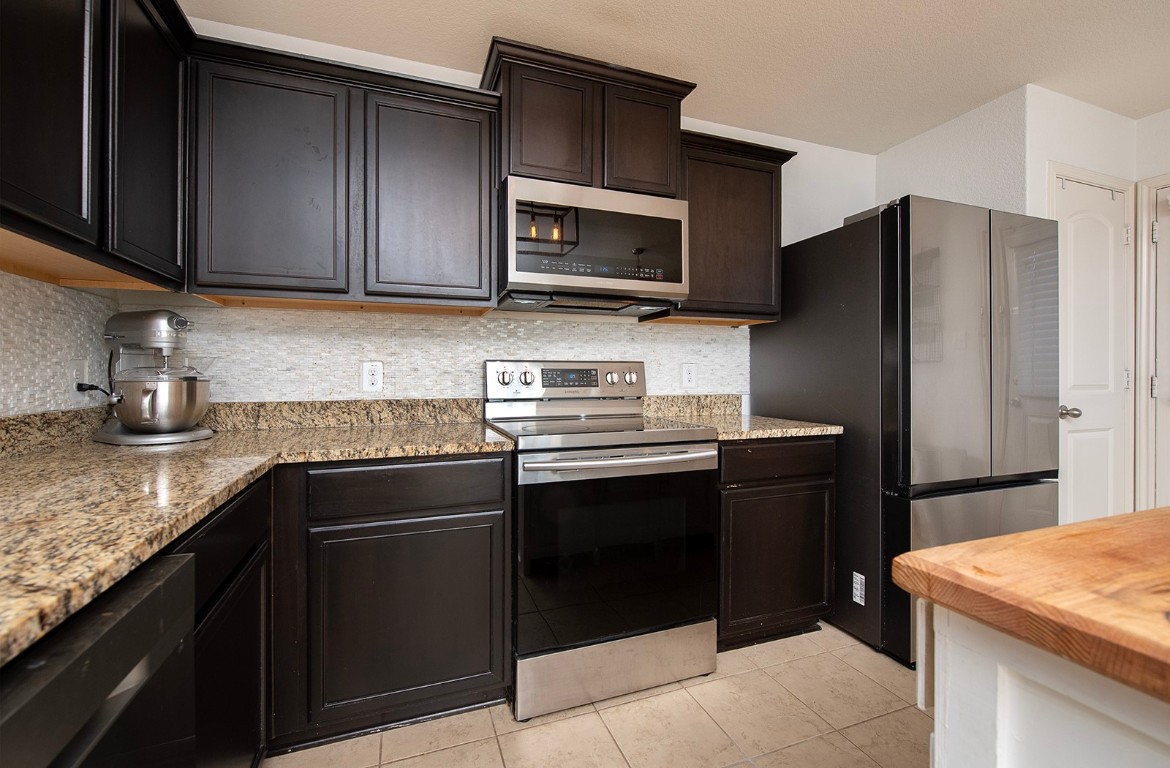 216 Millers Loop Jarrell, TX 76537 - Photo 9 of 31 Kitchen with stainless steel appliances, granite counter, backsplash, and tile flooring