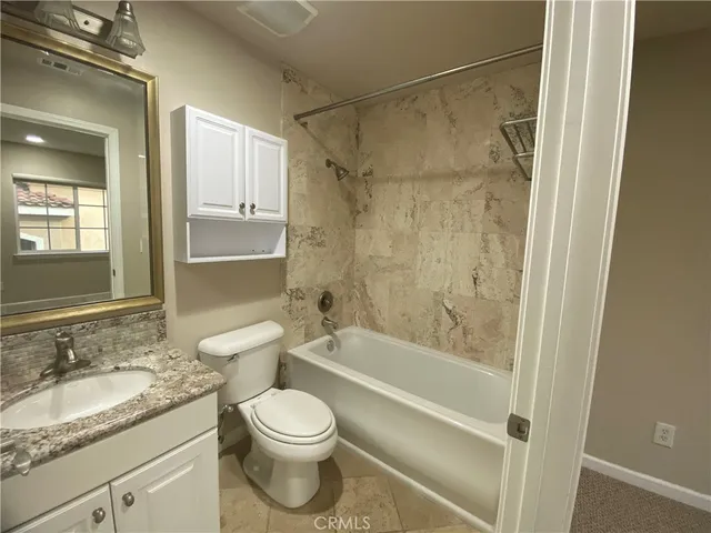 a bathroom with a granite countertop toilet a sink and a bathtub
