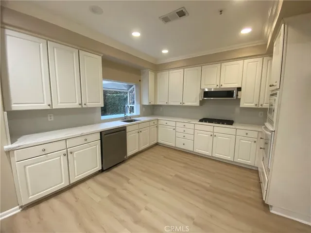 a kitchen with white cabinets stainless steel appliances and sink
