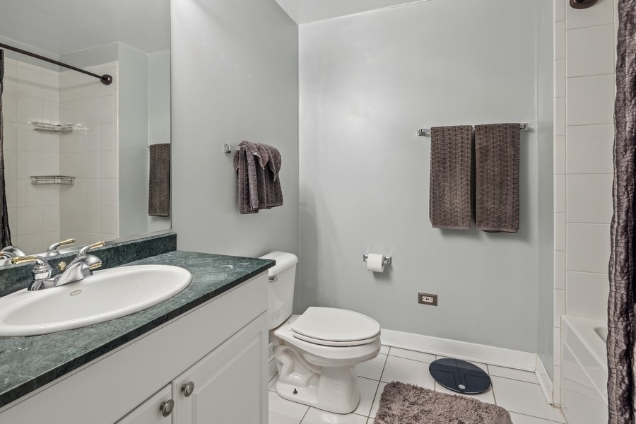 910 West Madison Street, Unit 602 Chicago, IL 60607 - Photo 13 of 15 a bathroom with a granite countertop sink a toilet a mirror and shower