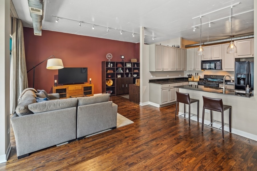 910 West Madison Street, Unit 602 Chicago, IL 60607 - Photo 4 of 15 a living room with stainless steel appliances kitchen island granite countertop furniture and a wooden floor