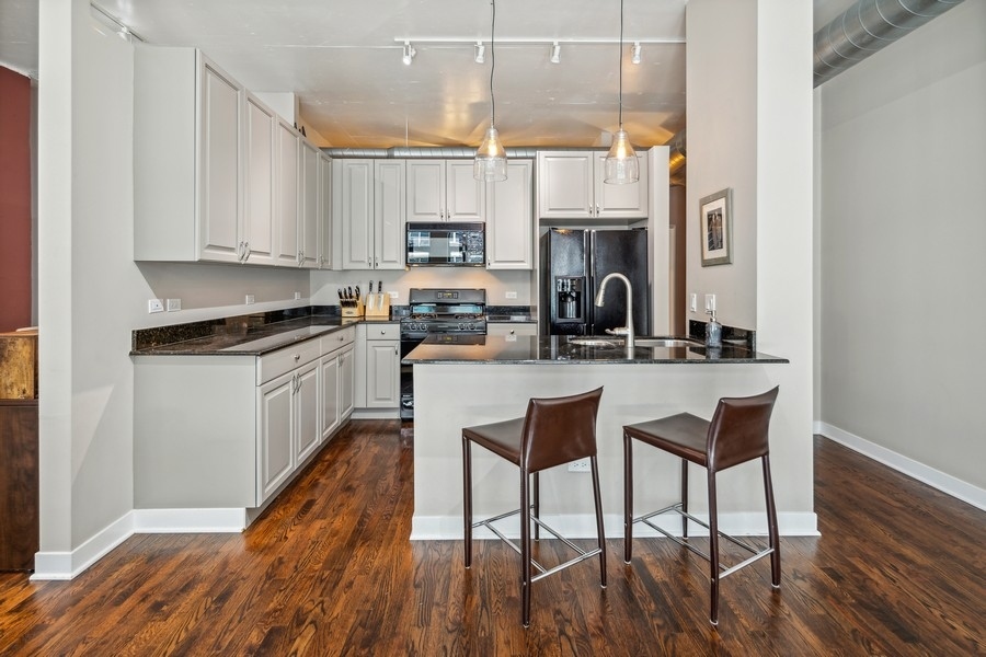 910 West Madison Street, Unit 602 Chicago, IL 60607 - Photo 6 of 15 a kitchen with a table chairs refrigerator and cabinets