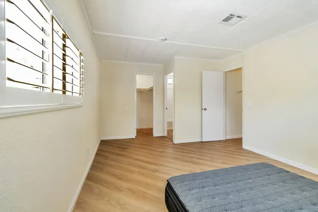 a view of an empty room with wooden floor and a window