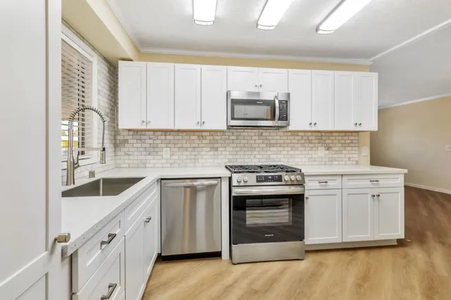 a kitchen with white cabinets and stainless steel appliances