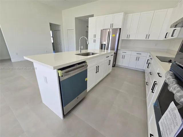 a kitchen with stainless steel appliances granite countertop a sink a stove and white cabinets