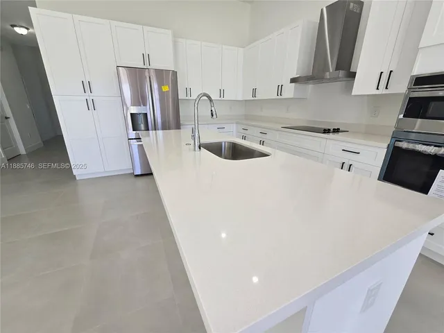 a kitchen with stainless steel appliances granite countertop a sink a stove and white cabinets
