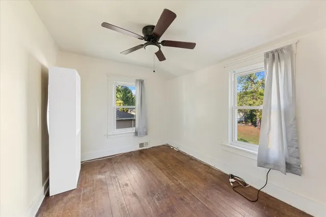 a view of an empty room with a window and wooden floor