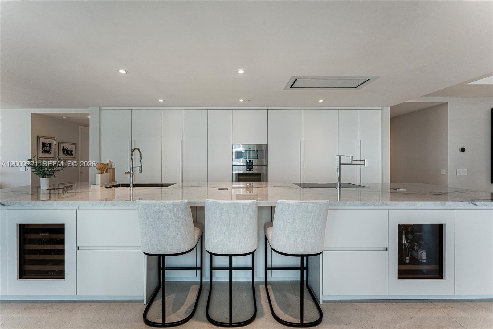 9349 Collins Avenue, Unit 801 Surfside, FL 33154 - Photo 15 of 59 a kitchen with stainless steel appliances kitchen island granite countertop a table chairs in it and white cabinets