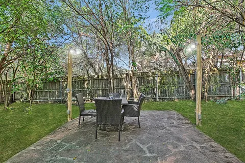 a view of a backyard with table and chairs and a large tree