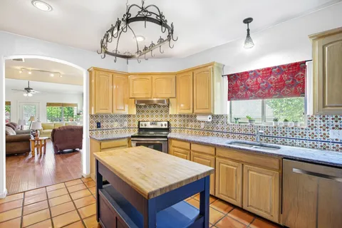a kitchen with stainless steel appliances granite countertop a stove a sink dishwasher and white cabinets with wooden floor
