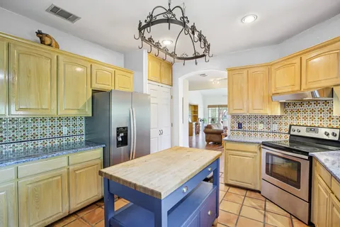 a kitchen with stainless steel appliances granite countertop a sink a stove cabinets counter space and a window