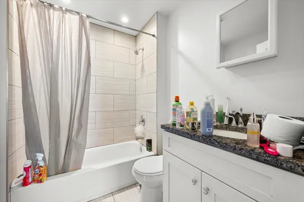 a bathroom with a bathtub sink vanity mirror and toilet