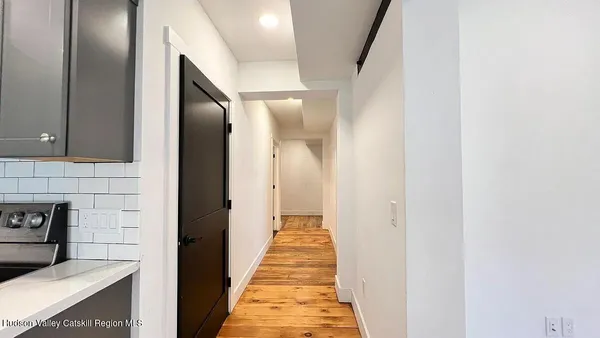 a view of a hallway with wooden floor and a bathroom